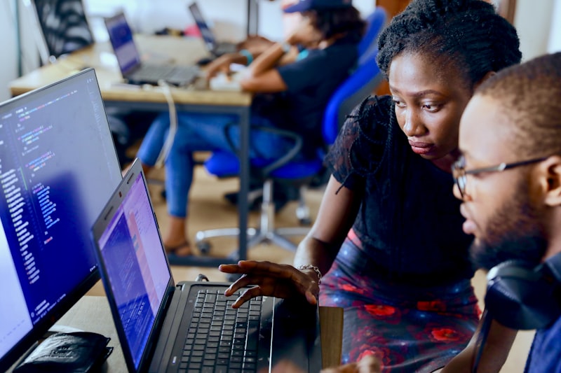 Two developers reviewing code together on a laptop
